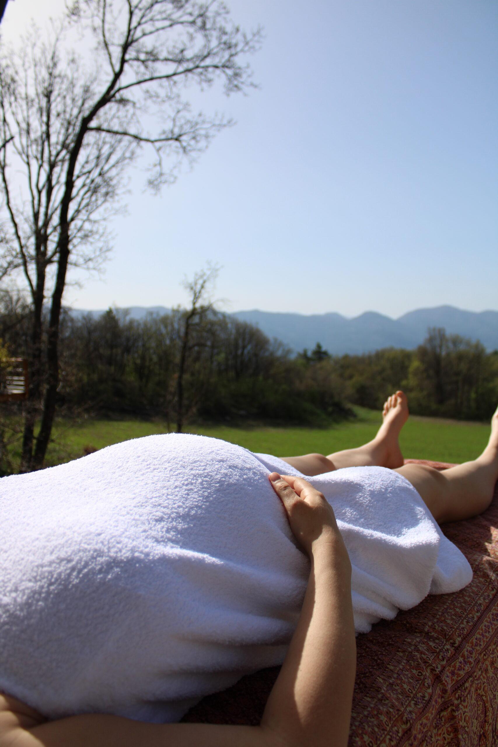 Femme enceinte allongée sur une table de massage, le ventre couvert d’une serviette